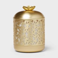 a gold canister with a flower on the top and leaves on the bottom, sitting in front of a white background