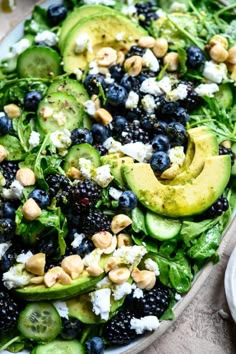 a salad with blueberries, cucumbers, avocado and feta cheese