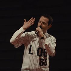 a man standing in front of a microphone while holding his hands up to the side