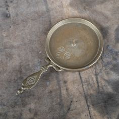 an old metal pan sitting on top of a wooden table next to a bottle opener