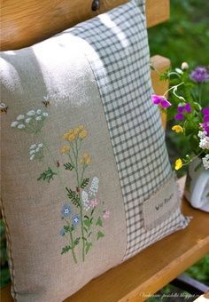 a pillow with flowers on it sitting on a bench next to a potted plant