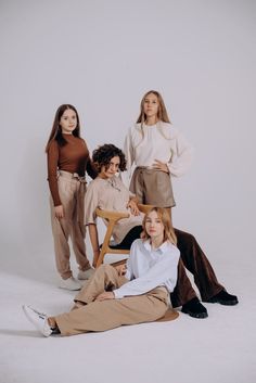 four young women posing for a photo in front of a white background with one sitting on the floor