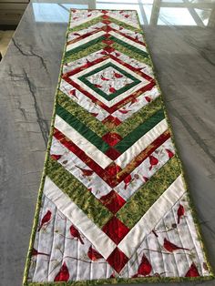 a long table runner with red, green and white quilted designs on the edge