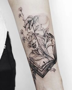 a woman with a book and flowers tattoo on her arm