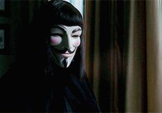 a person wearing a mask with long black hair and dark eyes looking out the window