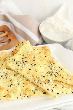 there are some crackers on the plate and a bowl of yogurt in the background