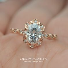 a close up of a person's hand holding an engagement ring with a diamond center