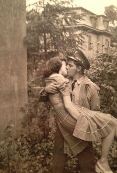 an old black and white photo of a man kissing a woman