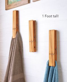 three towels hanging on the wall next to two wooden hooks