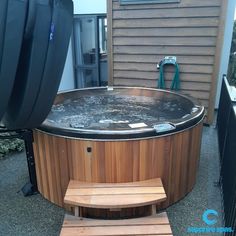 a hot tub sitting on top of a patio next to a wooden bench and trash can