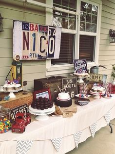 a table topped with lots of desserts next to a window covered in signs and decorations