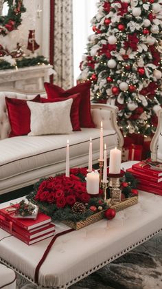 a living room decorated for christmas with red and white decorations on the coffee table, lit by candles