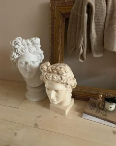 two busturines sitting next to a mirror on top of a wooden floor