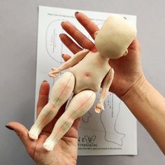 a person holding a doll in their left hand and the other hand is showing it's skin