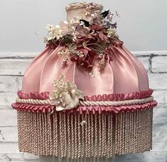 a pink and gold dress with flowers on the top is sitting against a white brick wall