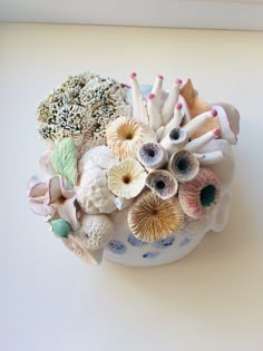 an arrangement of seashells and corals in a bowl on a white surface