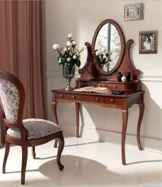 a desk with a mirror, chair and flowers on it