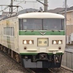 a green and white train traveling down tracks