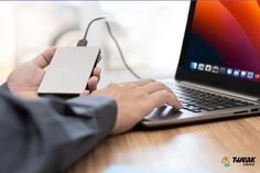 a person using a laptop computer with an external hard drive attached to it