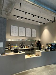 a restaurant counter with menus on the wall and lights hanging from the ceiling above it