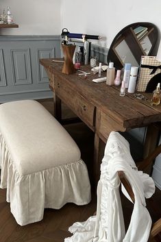 a wooden table topped with lots of clutter next to a mirror and vanity area