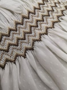 an image of a bed with white sheets and crochet on the bottom half