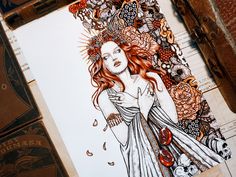 a drawing of a woman surrounded by flowers and skulls on a piece of white paper