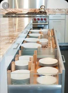 an open drawer in the middle of a kitchen with plates and bowls on it's side