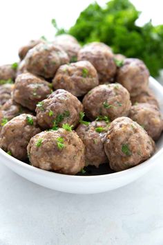 a white bowl filled with meatballs and parsley