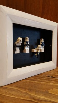 three legos are in a shadow box on a table