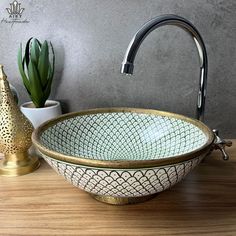 a bowl shaped sink sitting on top of a wooden counter next to a potted plant