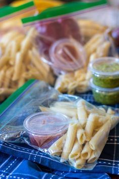 some pasta and other food items on a blue table cloth with plastic wrap around them