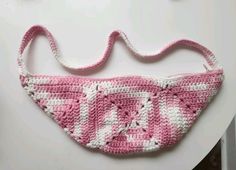 a crocheted pink and white purse sitting on top of a table next to a pair of scissors