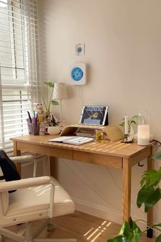 a wooden desk with a laptop computer on top of it next to a plant and window