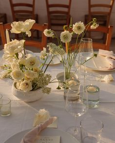 the table is set with white flowers and place settings