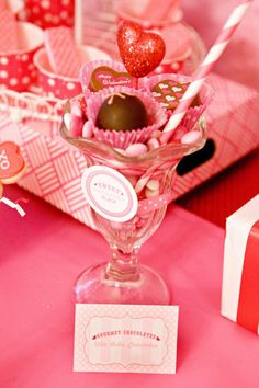 valentine's day candy in a wine glass on a pink tablecloth with red and white boxes