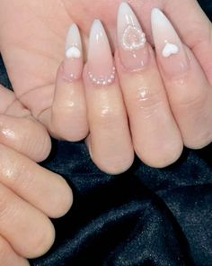 two hands with white and pink nail polish on them