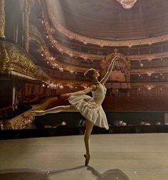 a ballerina in a white dress is performing on stage with an ornate chandelier