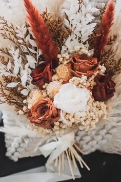 a bridal bouquet with feathers and flowers on it's lapel, ready to be used as a wedding bouquet