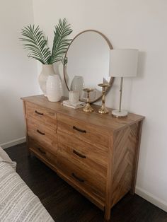 a wooden dresser with two lamps and a round mirror on it's sideboard