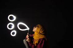 a woman in a yellow scarf is holding a lite up object with circles on it