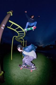 two skateboarders are doing tricks on the grass