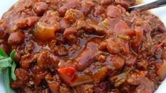 a white bowl filled with chili and meat on top of a green leafy table