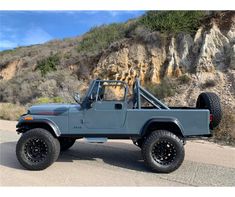 a blue jeep parked in front of a mountain