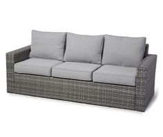 an outdoor sofa with grey cushions and pillows on the back, in front of a white background