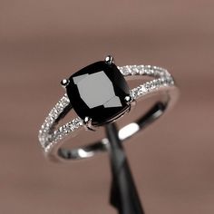 a black and white ring sitting on top of a piece of wood with diamonds around it