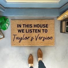 a person standing next to a door mat that says in this house we listen to taylor's version