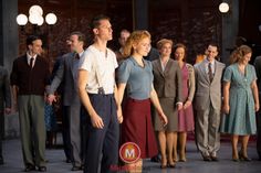 a group of people standing next to each other in front of a man wearing a suit and tie