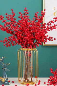 a vase with red berries in it sitting on a table