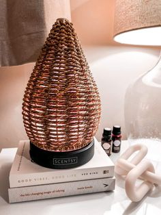 a wicker lamp sitting on top of a book next to an empty bottle and two bottles